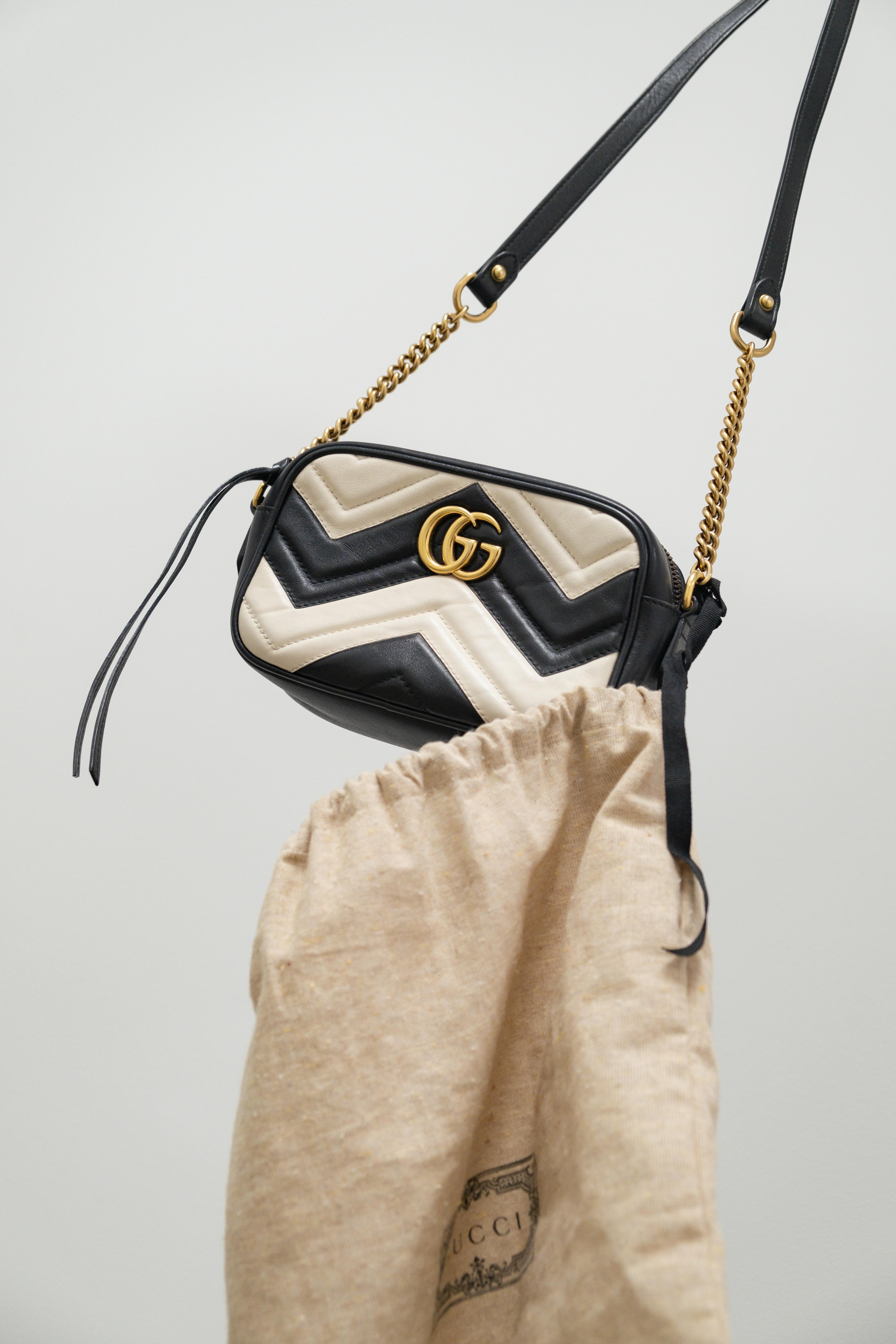 Designer handbag with gold chain strap on a light gray background